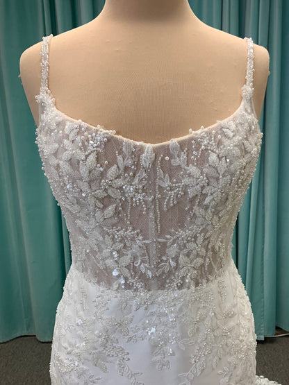 Marjorie ivory spaghetti strap wedding dress on mannequin with illusion corset bodice, floral lace appliqués, and scoop neckline.
