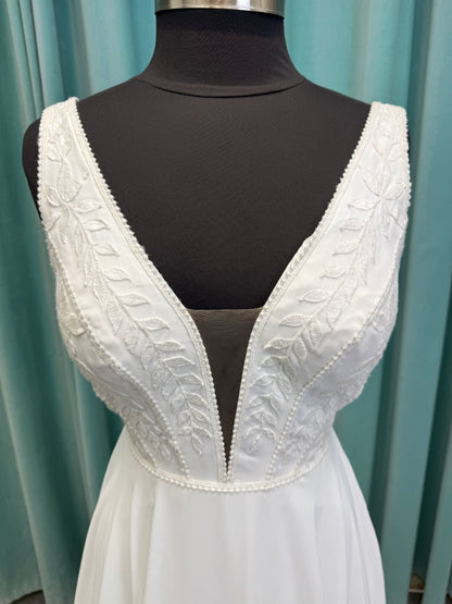 Martha My Dear ivory sleeveless V-neck A-line wedding dress on mannequin with geometric lace bodice panel and flowing chiffon skirt.
