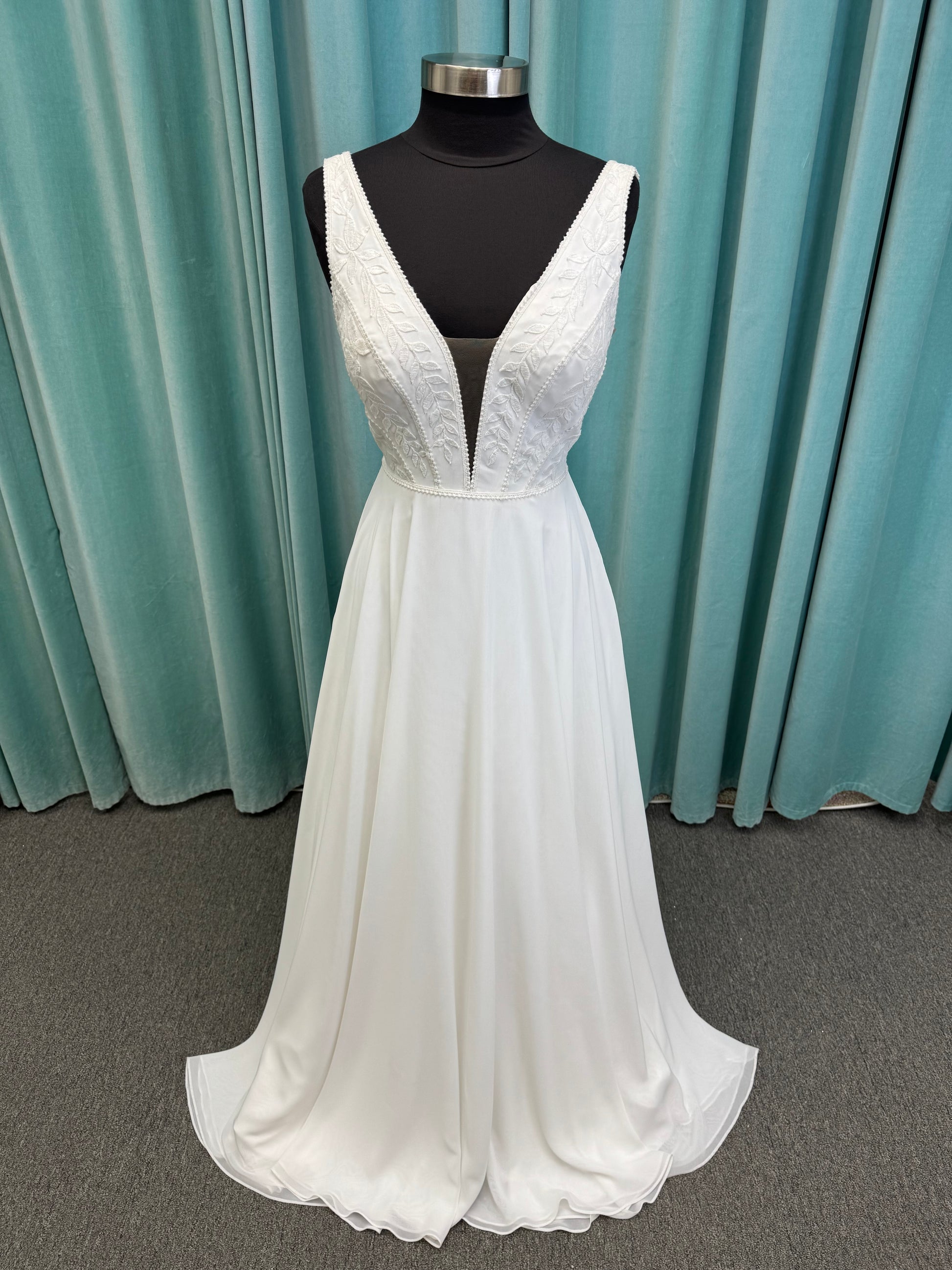 Martha My Dear ivory sleeveless V-neck A-line wedding dress on mannequin with geometric lace bodice panel and flowing chiffon skirt.
