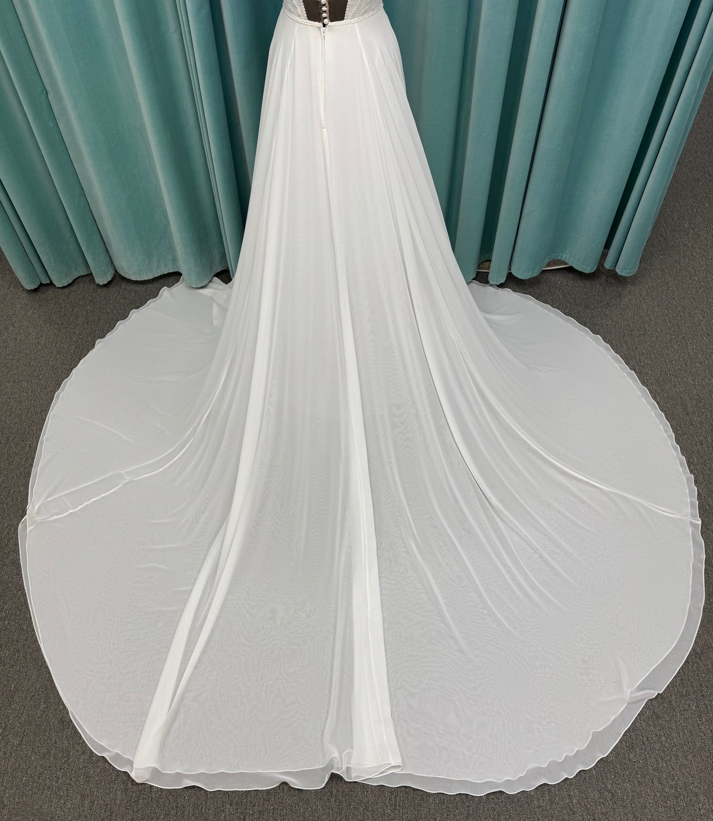 Martha My Dear ivory sleeveless V-neck A-line wedding dress on mannequin with geometric lace bodice panel and flowing chiffon skirt.
