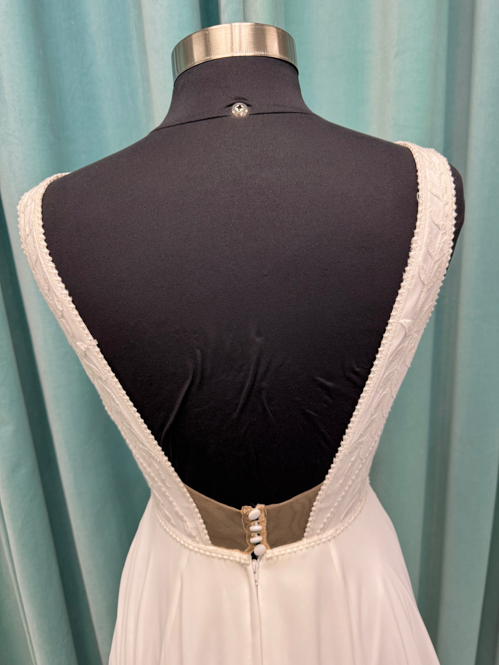 Martha My Dear ivory sleeveless V-neck A-line wedding dress on mannequin with geometric lace bodice panel and flowing chiffon skirt.
