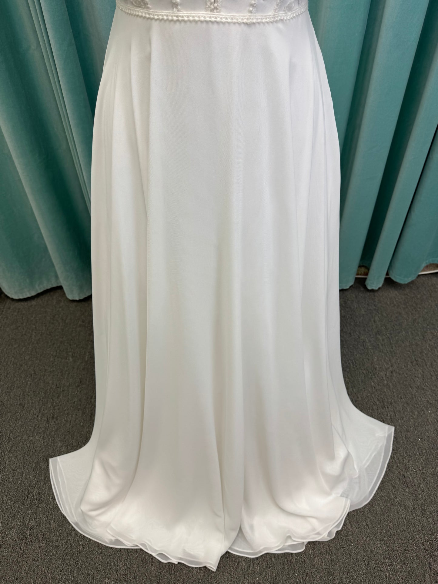Martha My Dear ivory sleeveless V-neck A-line wedding dress on mannequin with geometric lace bodice panel and flowing chiffon skirt.
