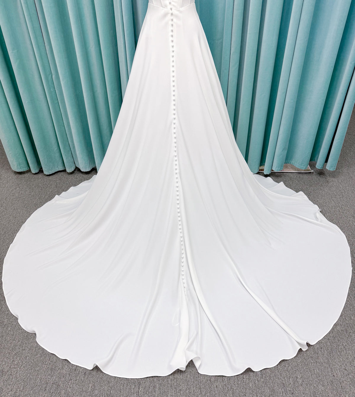 Crepe A-line wedding dress with spaghetti straps, draped V-neckline, ruched bodice, defined waist, and flowing skirt.