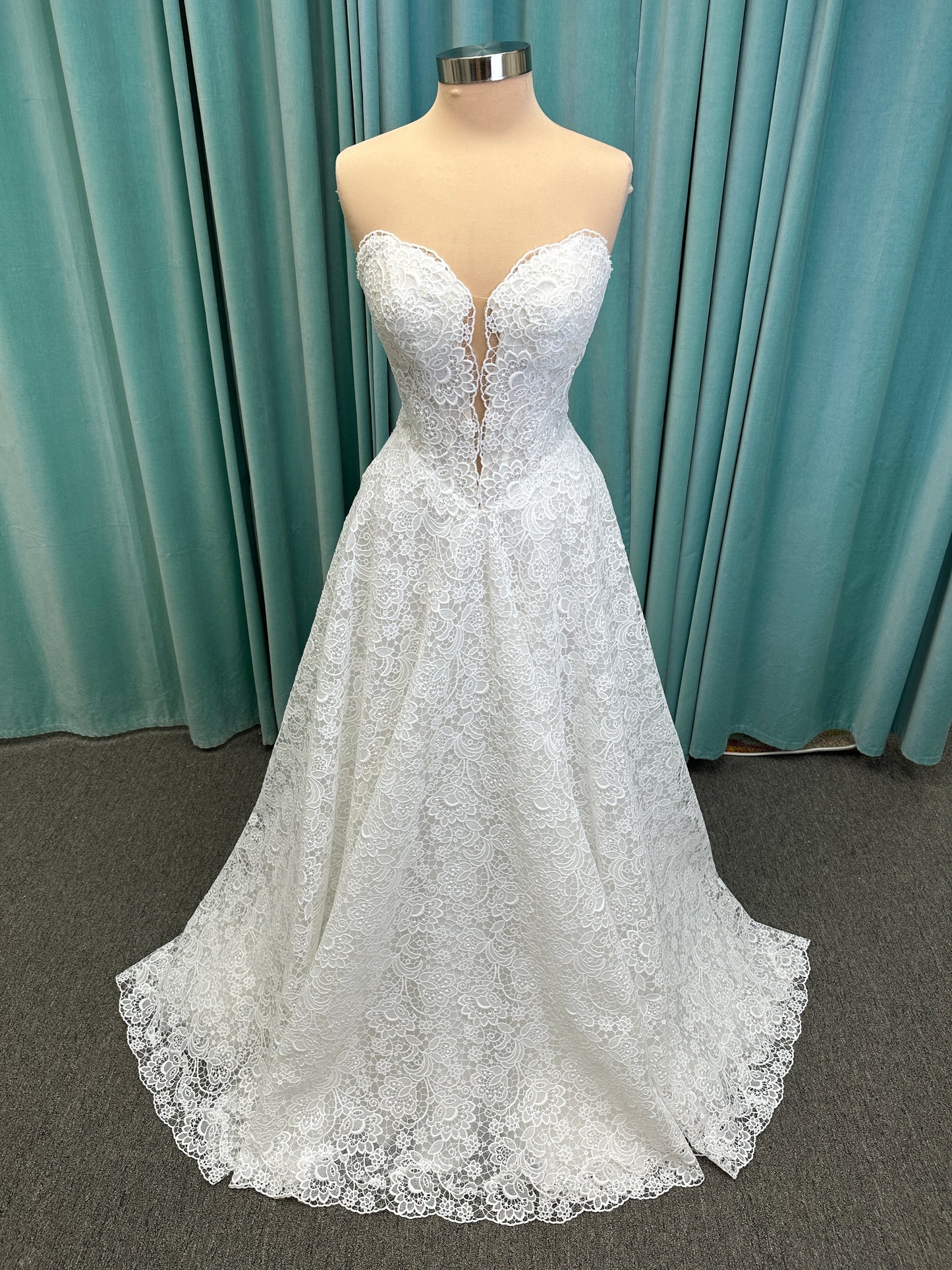 Min ivory strapless sweetheart lace A-line wedding dress on mannequin with illusion corset bodice and voluminous lace skirt.
