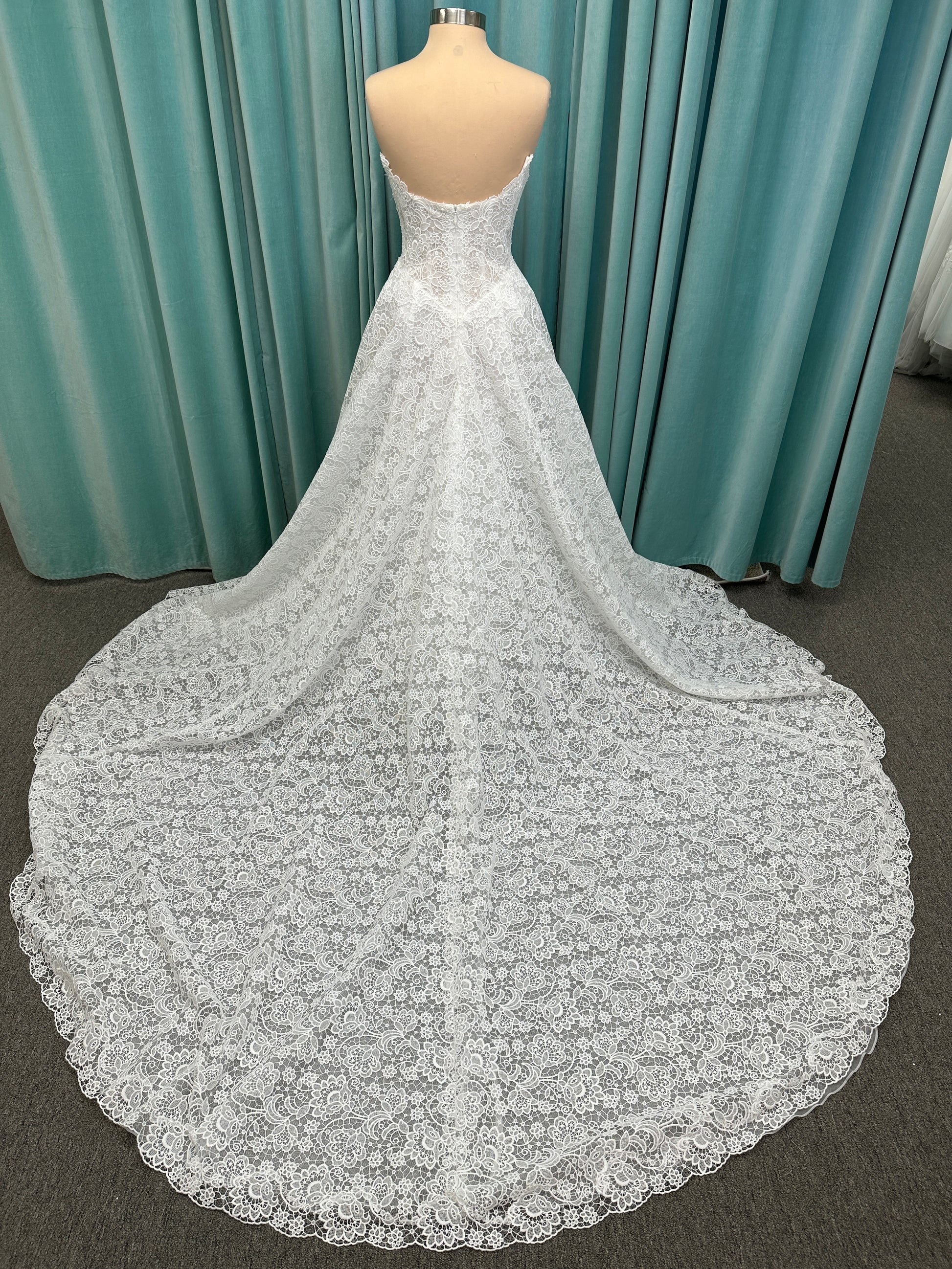 Min ivory strapless sweetheart lace A-line wedding dress on mannequin with illusion corset bodice and voluminous lace skirt.
