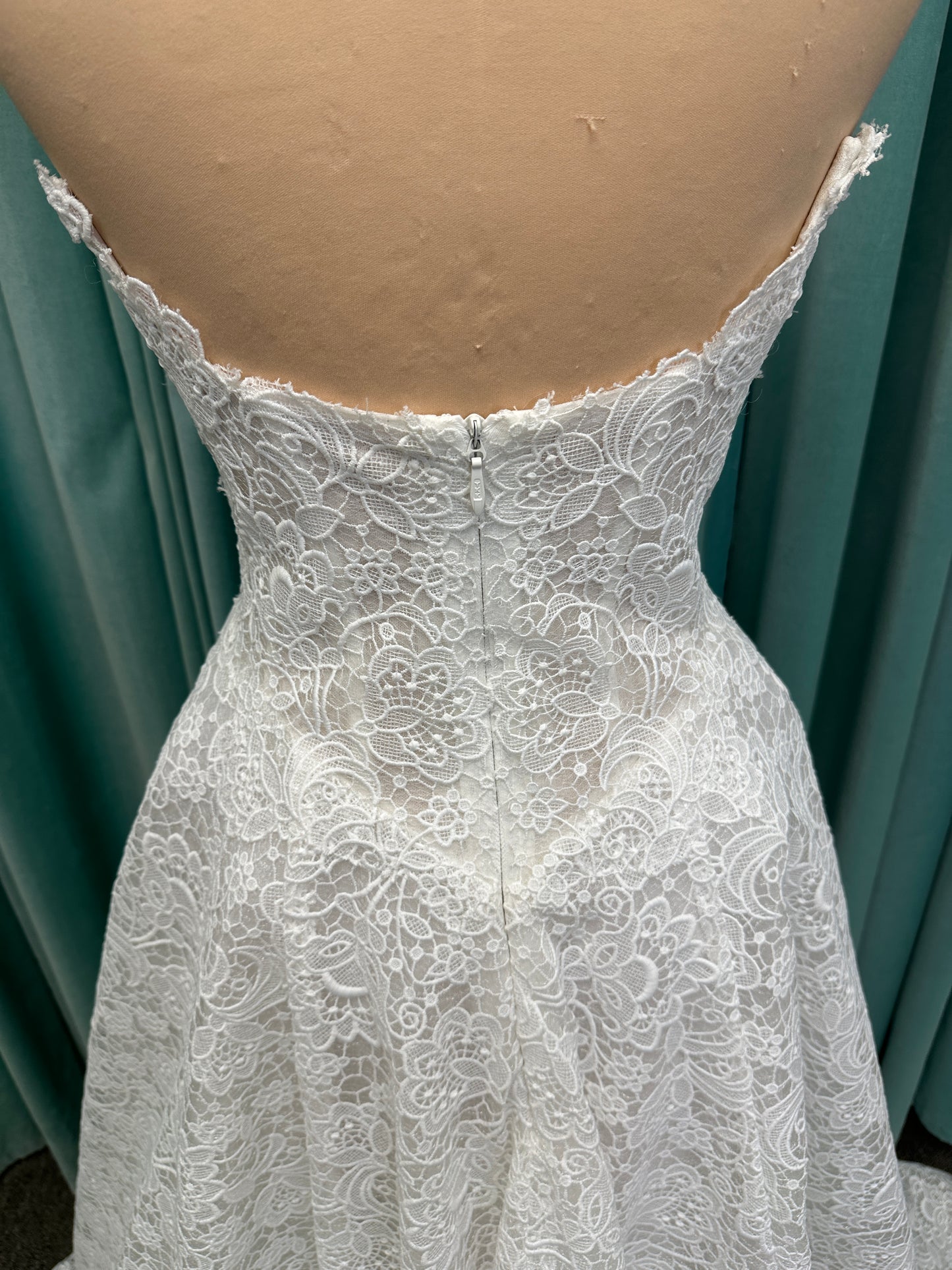 Min ivory strapless sweetheart lace A-line wedding dress on mannequin with illusion corset bodice and voluminous lace skirt.
