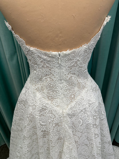 Min ivory strapless sweetheart lace A-line wedding dress on mannequin with illusion corset bodice and voluminous lace skirt.
