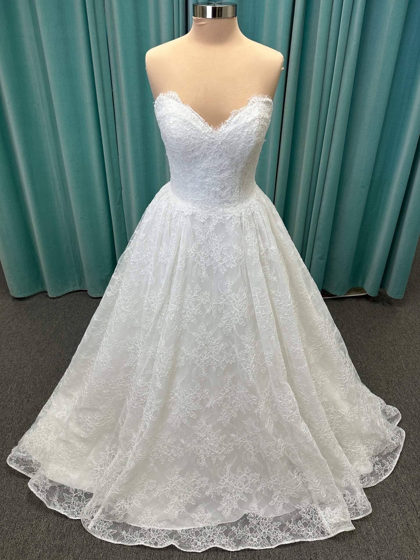 Moira ivory strapless sweetheart ballgown wedding dress on mannequin with sparkle lace detail and full voluminous skirt.
