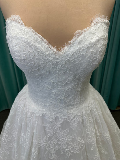 Moira ivory strapless sweetheart ballgown wedding dress on mannequin with sparkle lace detail and full voluminous skirt.
