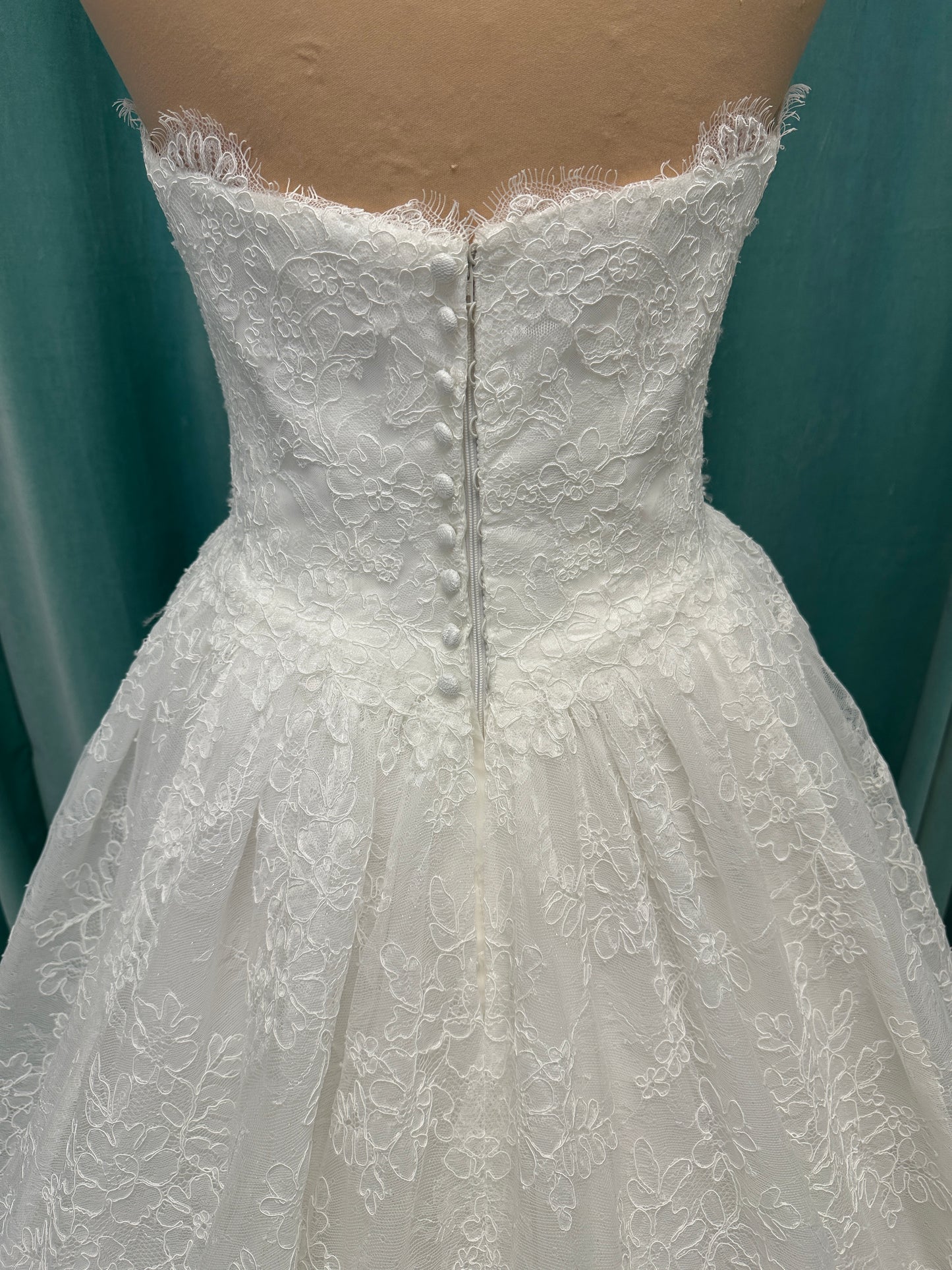 Moira ivory strapless sweetheart ballgown wedding dress on mannequin with sparkle lace detail and full voluminous skirt.
