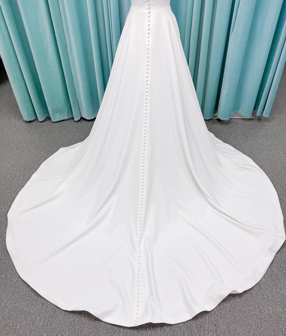 Minimalist crepe A-line wedding dress with spaghetti straps, V-neckline, fitted bodice, natural waist, and flowing skirt.