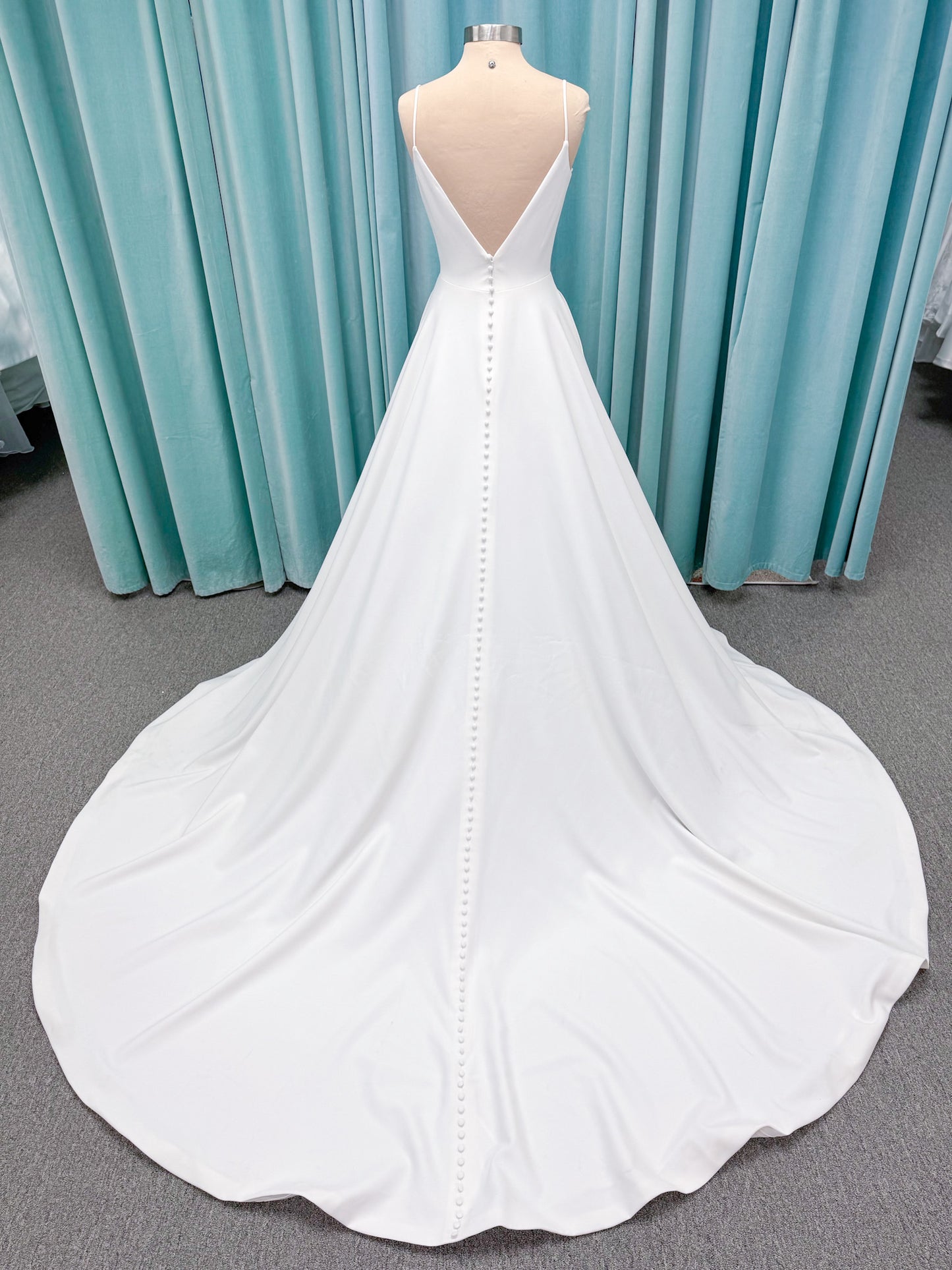 Minimalist crepe A-line wedding dress with spaghetti straps, V-neckline, fitted bodice, natural waist, and flowing skirt.