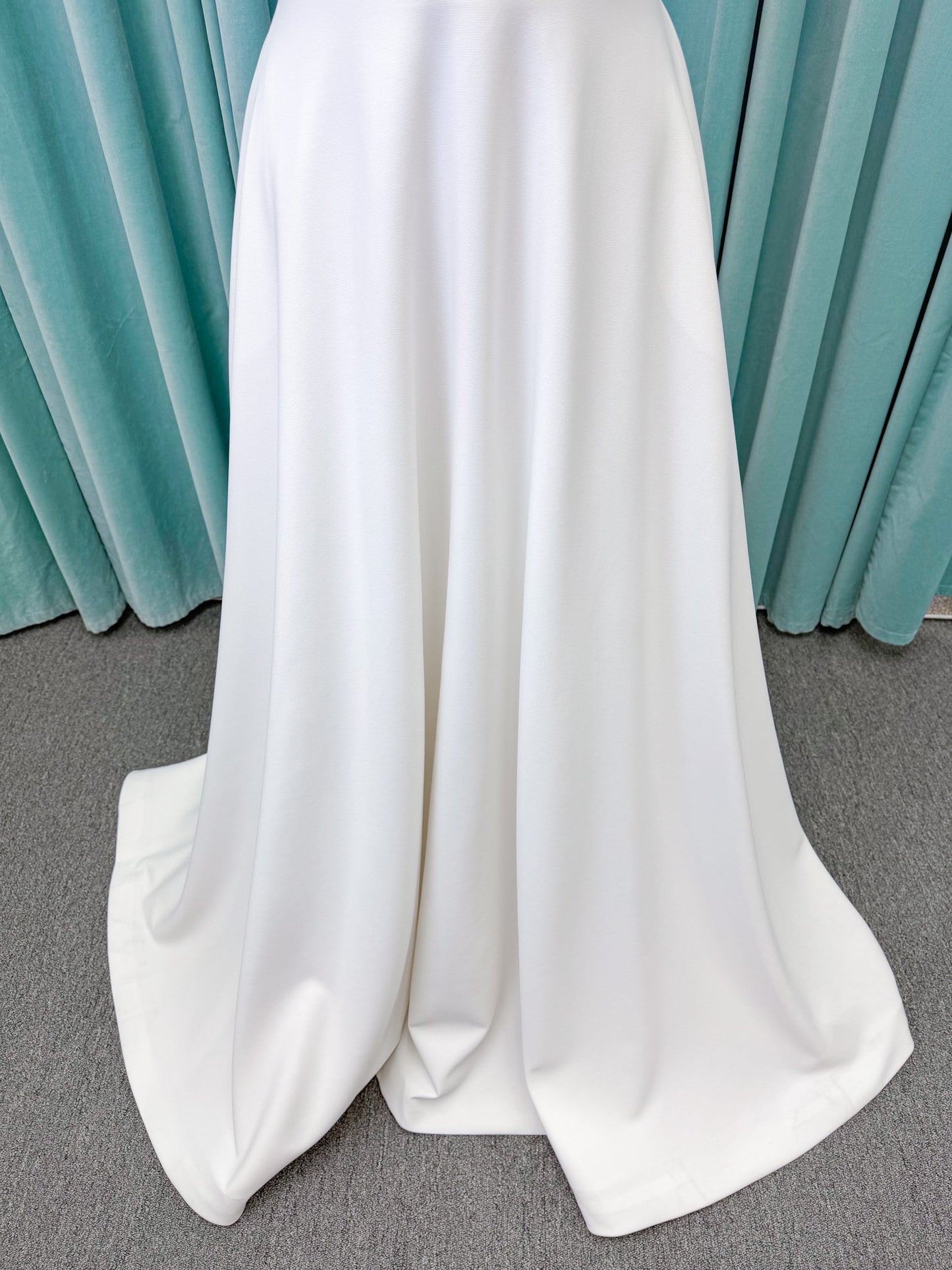 Minimalist crepe A-line wedding dress with spaghetti straps, V-neckline, fitted bodice, natural waist, and flowing skirt.