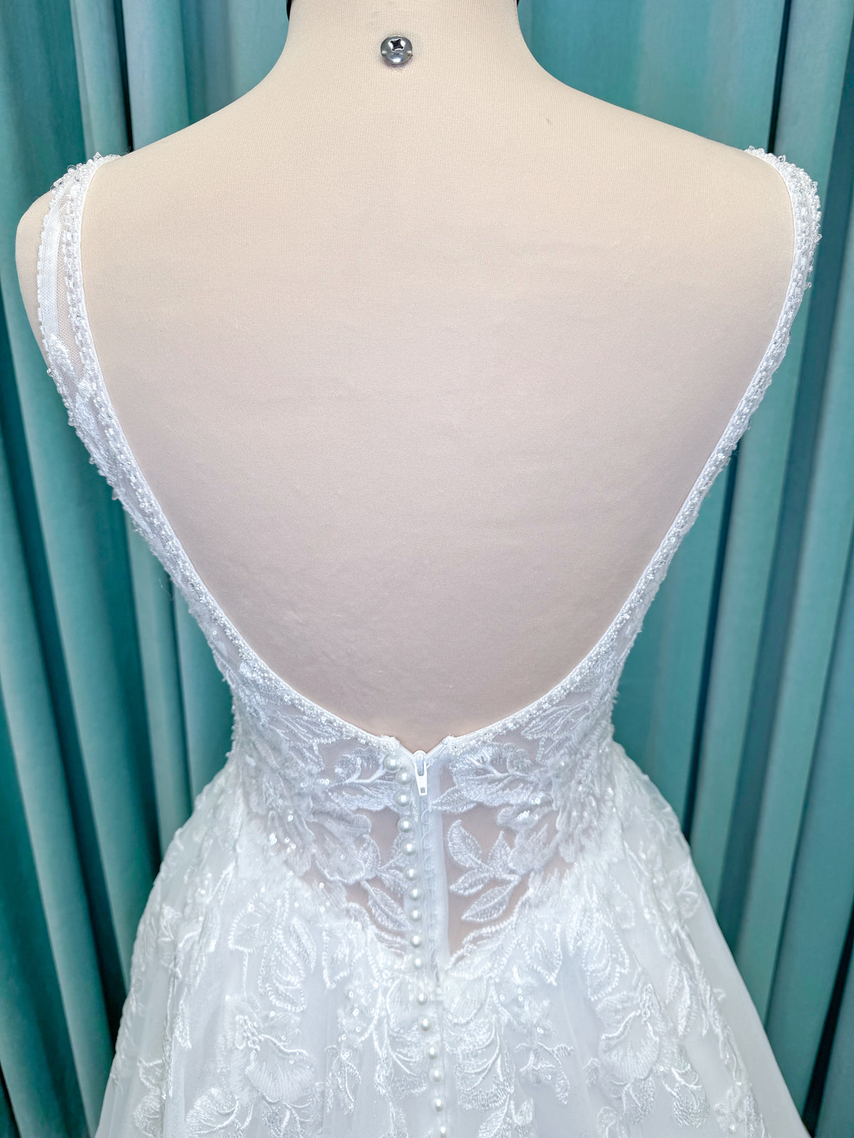 Morilee 1010021 Myrtha A-line wedding dress on mannequin with plunging V-neckline, sheer low scoop back, and glitter tulle lace applique