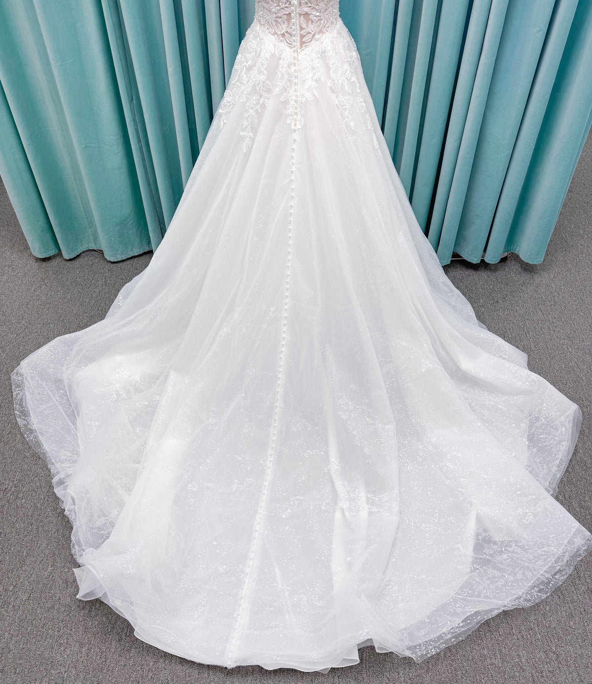 Morilee 1010021 Myrtha A-line wedding dress on mannequin with plunging V-neckline, sheer low scoop back, and glitter tulle lace applique