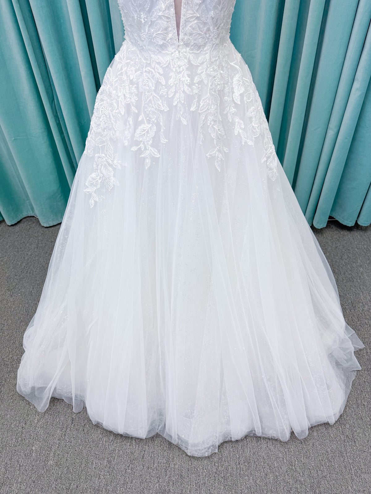 Morilee 1010021 Myrtha A-line wedding dress on mannequin with plunging V-neckline, sheer low scoop back, and glitter tulle lace applique