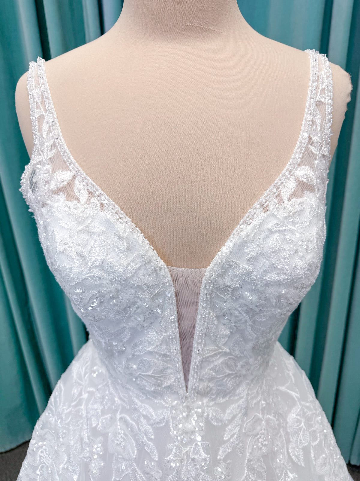 Morilee 1010021 Myrtha A-line wedding dress on mannequin with plunging V-neckline, sheer low scoop back, and glitter tulle lace applique
