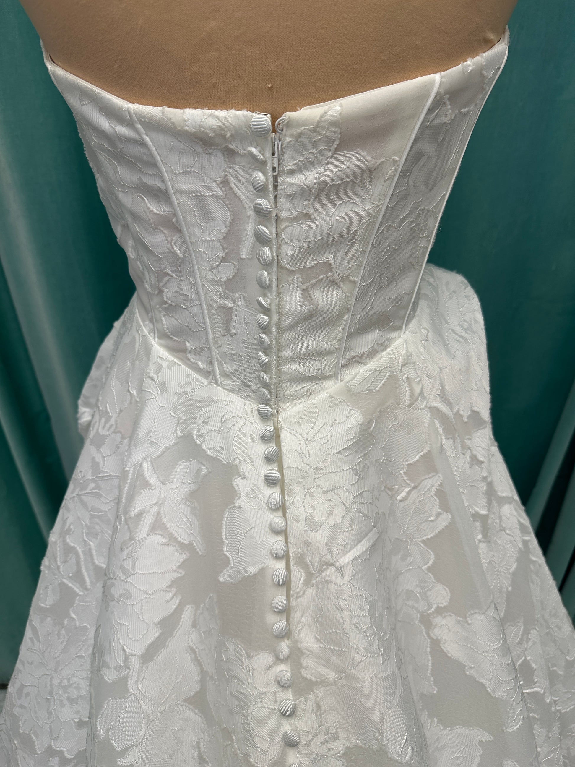 Palmer ivory strapless sweetheart A-line wedding dress on mannequin in jacquard fabric with a front thigh-high slit.
