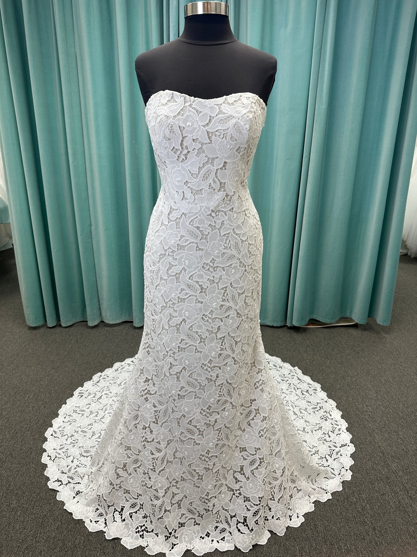 Patty ivory strapless sheath wedding dress on mannequin with sweetheart neckline and lace detail.
