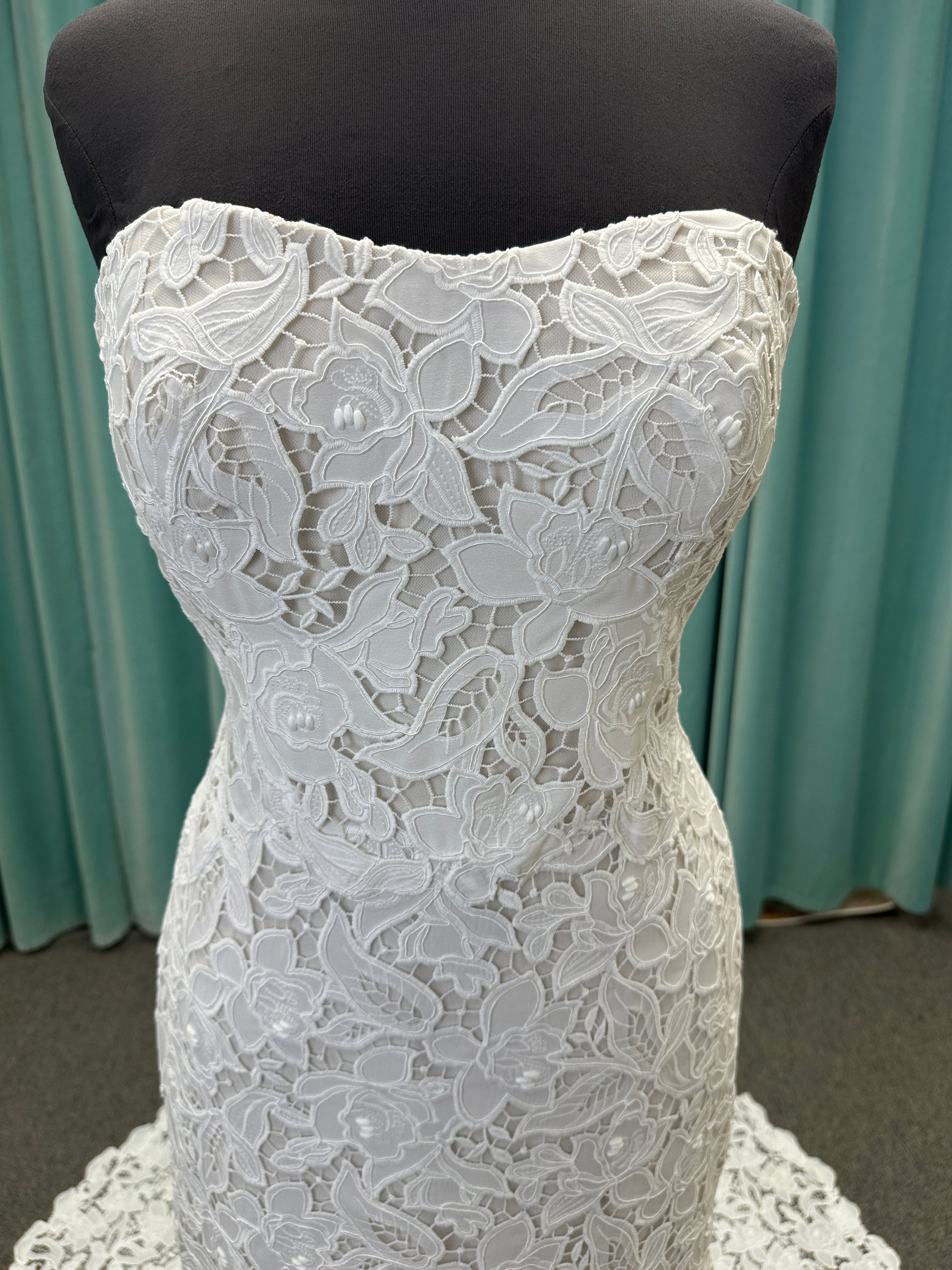 Patty ivory strapless sheath wedding dress on mannequin with sweetheart neckline and lace detail.
