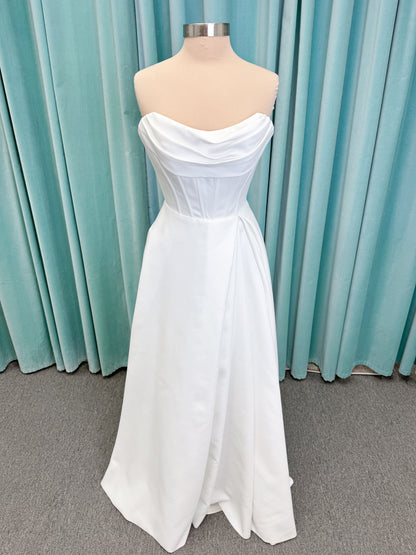 Morilee 15054 Pippa A-line wedding dress on mannequin with cowl neckline, corset bodice, petal satin skirt slit, and pockets