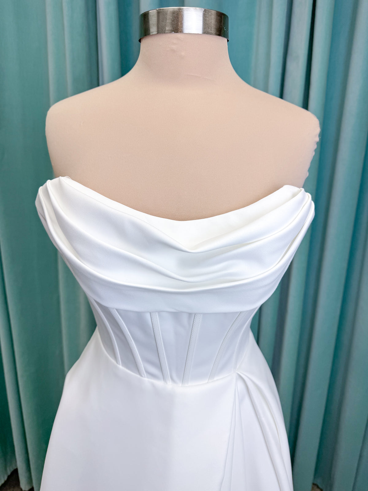 Morilee 15054 Pippa A-line wedding dress on mannequin with cowl neckline, corset bodice, petal satin skirt slit, and pockets
