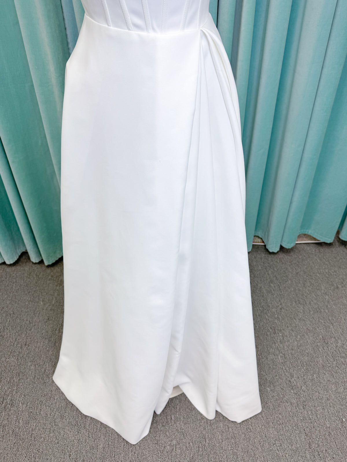 Morilee 15054 Pippa A-line wedding dress on mannequin with cowl neckline, corset bodice, petal satin skirt slit, and pockets