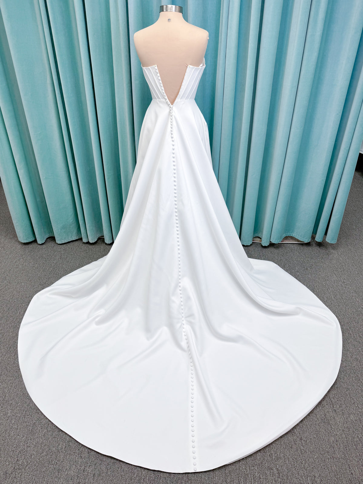 Morilee 15054 Pippa A-line wedding dress on mannequin with cowl neckline, corset bodice, petal satin skirt slit, and pockets