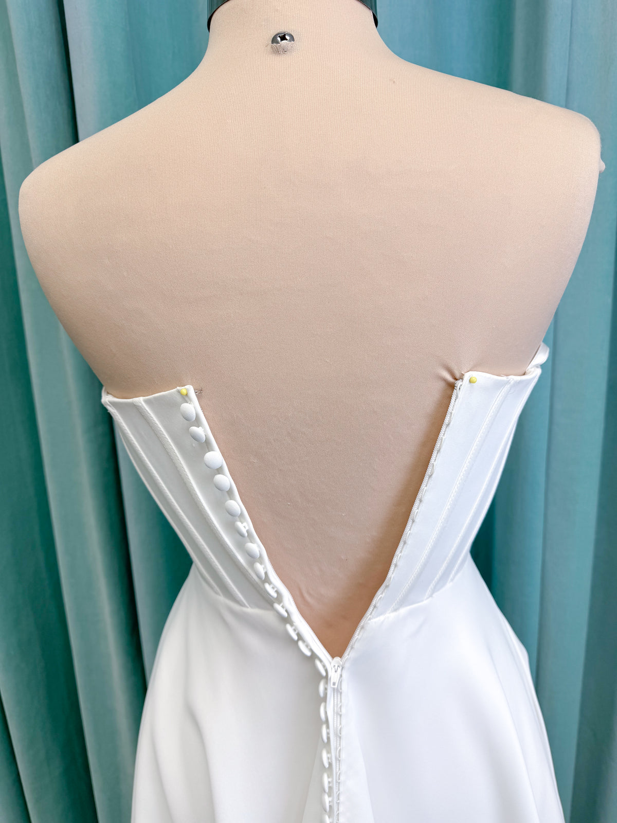 Morilee 15054 Pippa A-line wedding dress on mannequin with cowl neckline, corset bodice, petal satin skirt slit, and pockets