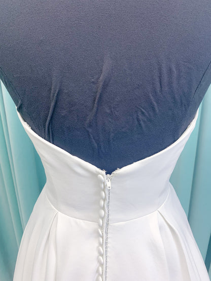 Morilee 4473 Reba A-line wedding dress in Larissa satin with cowl strapless neckline, detachable organza bow tie straps, and covered buttons to hem.