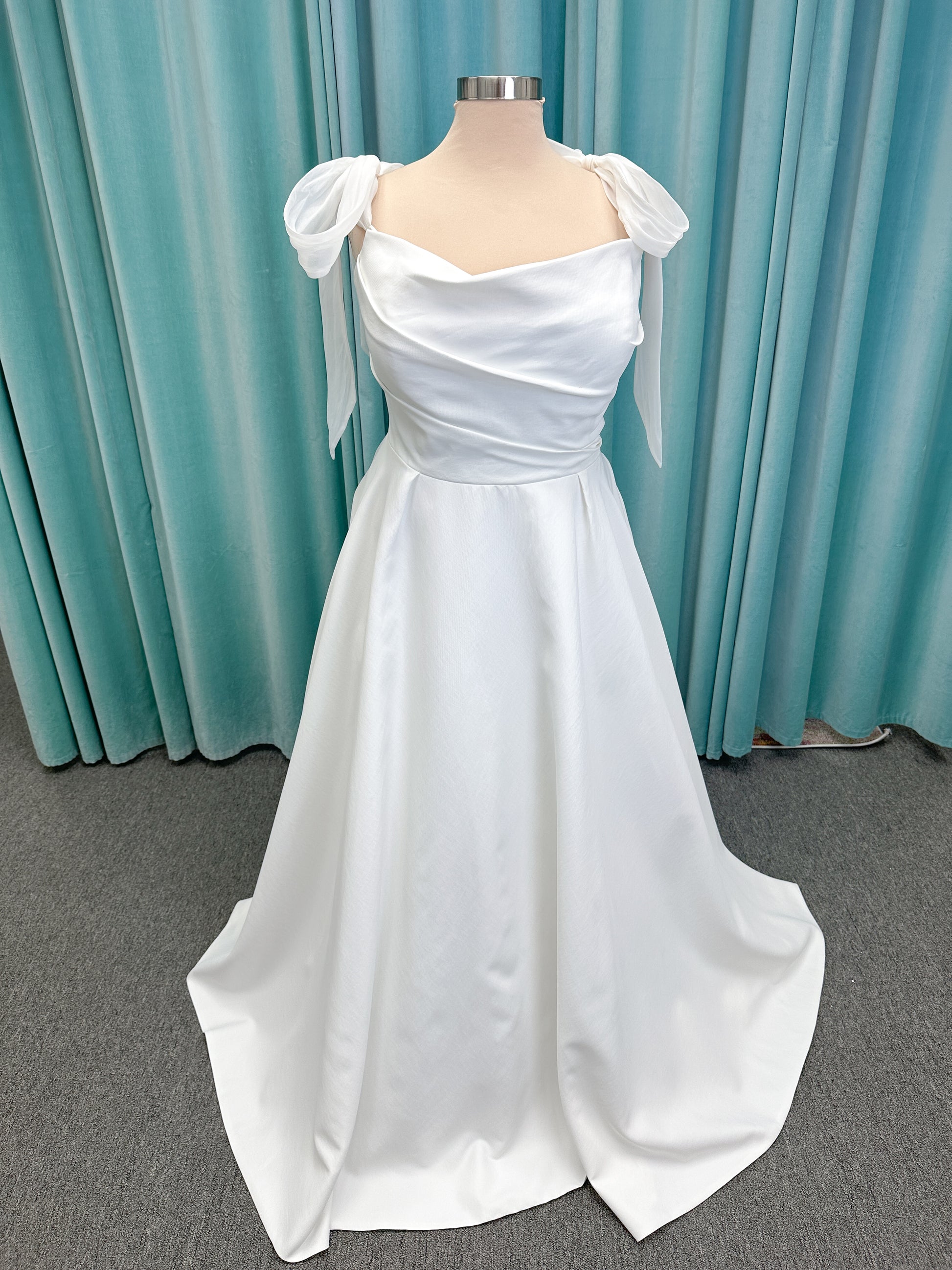Morilee 4473 Reba plus size A-line wedding dress in Larissa satin with cowl strapless neck, detachable organza bow tie straps, and covered buttons to hem.