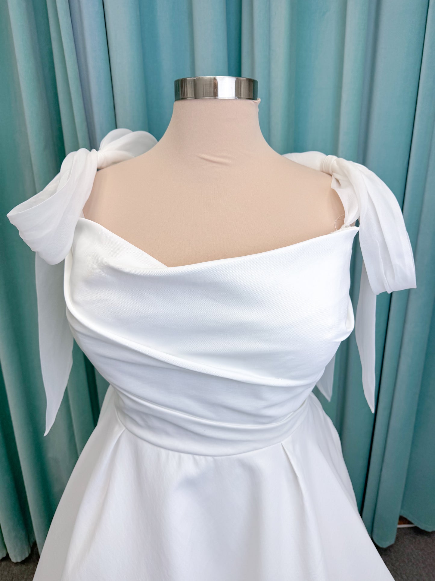 Morilee 4473 Reba plus size A-line wedding dress in Larissa satin with cowl strapless neck, detachable organza bow tie straps, and covered buttons to hem.