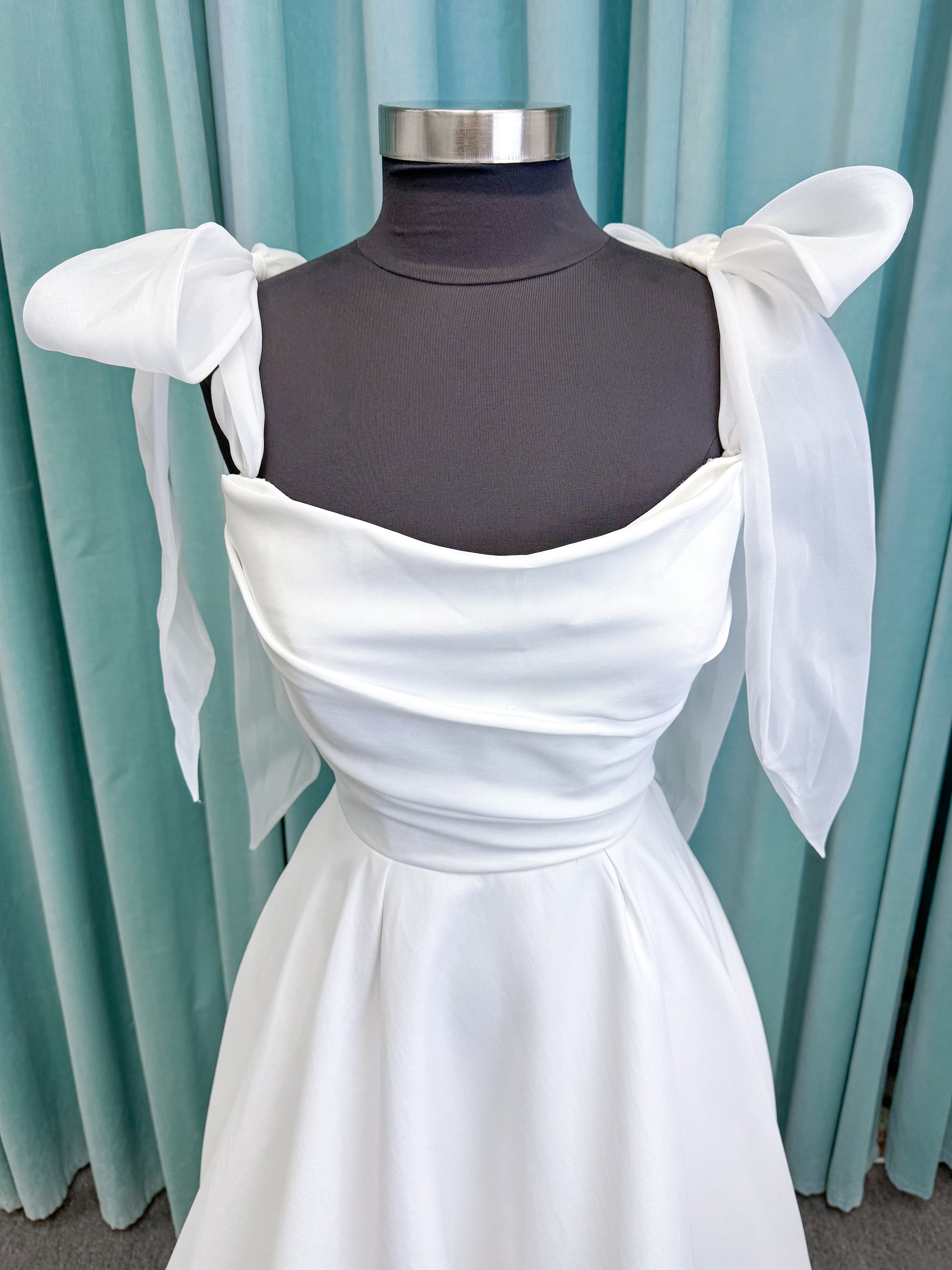 Morilee 4473 Reba A-line wedding dress in Larissa satin with cowl strapless neckline, detachable organza bow tie straps, and covered buttons to hem.