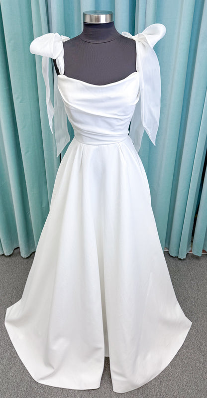 Morilee 4473 Reba A-line wedding dress in Larissa satin with cowl strapless neckline, detachable organza bow tie straps, and covered buttons to hem.