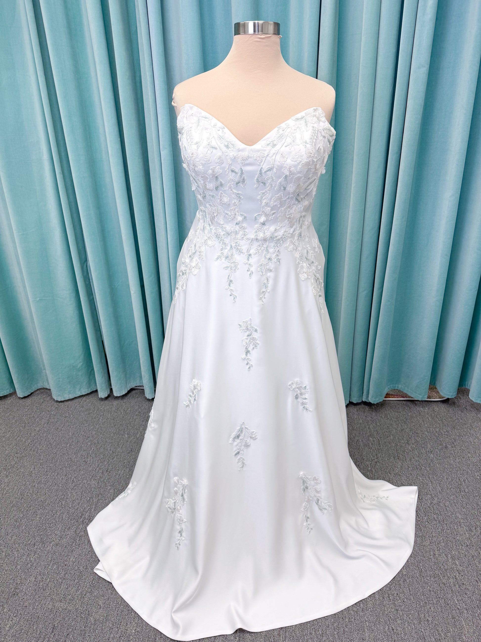 Morilee 4471 Roberta plus size wedding dress on mannequin with angular strapless neckline, 3D floral beaded embroidery, and satin A-line skirt