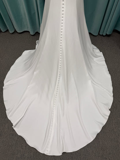 Stella York 8028 ivory lace fit-and-flare wedding dress on mannequin featuring high illusion neckline, sheer long lace sleeves, plunging bodice, and low open back.
