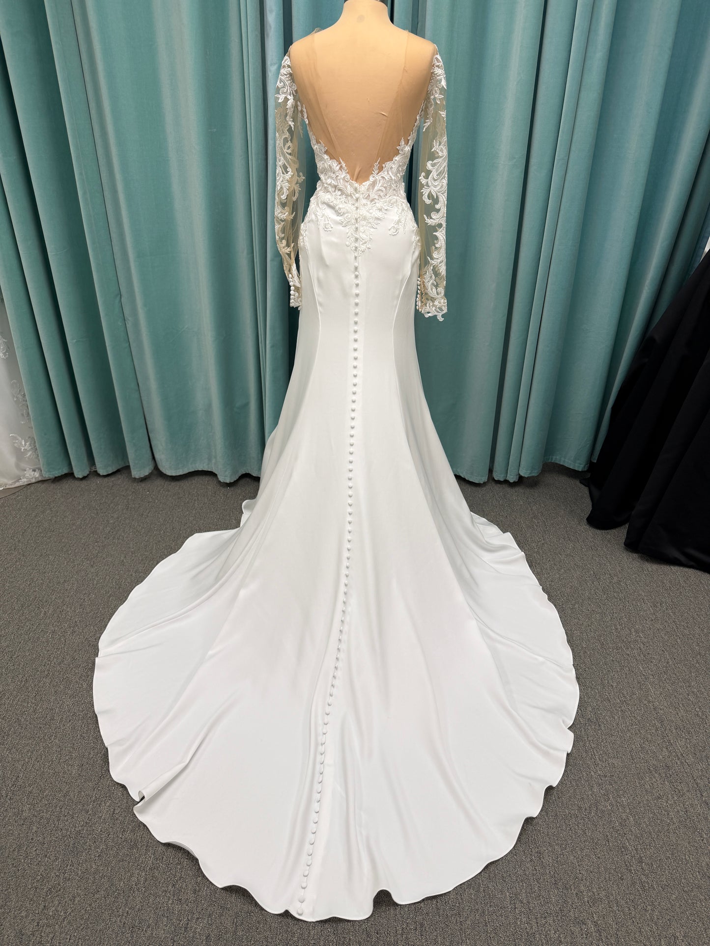 Stella York 8028 ivory lace fit-and-flare wedding dress on mannequin featuring high illusion neckline, sheer long lace sleeves, plunging bodice, and low open back.
