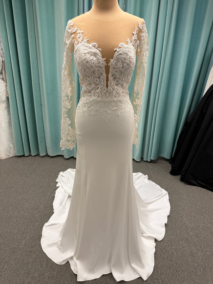 Stella York 8028 ivory lace fit-and-flare wedding dress on mannequin featuring high illusion neckline, sheer long lace sleeves, plunging bodice, and low open back.
