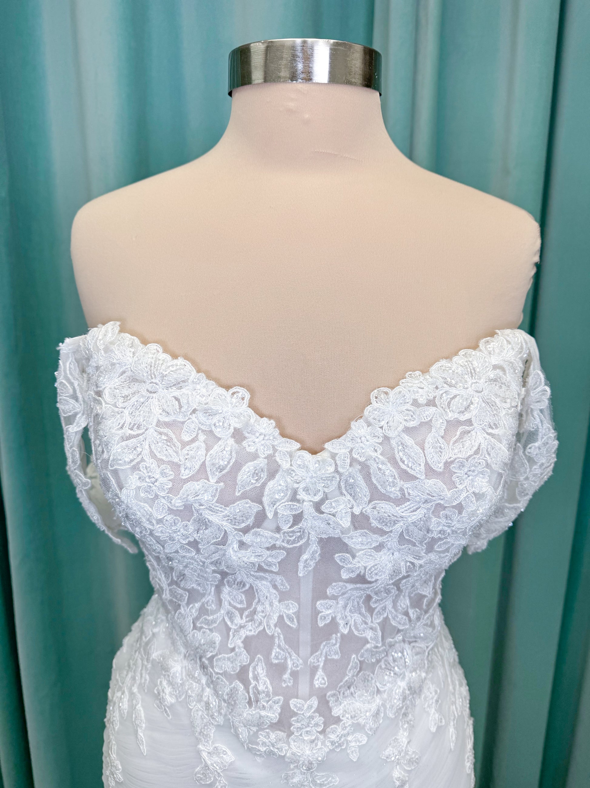 Morilee 4467 Rowena fit and flare wedding dress on mannequin with sheer corset bodice, frosted lace appliques, sweetheart neckline, and detachable off-the-shoulder sleeves
