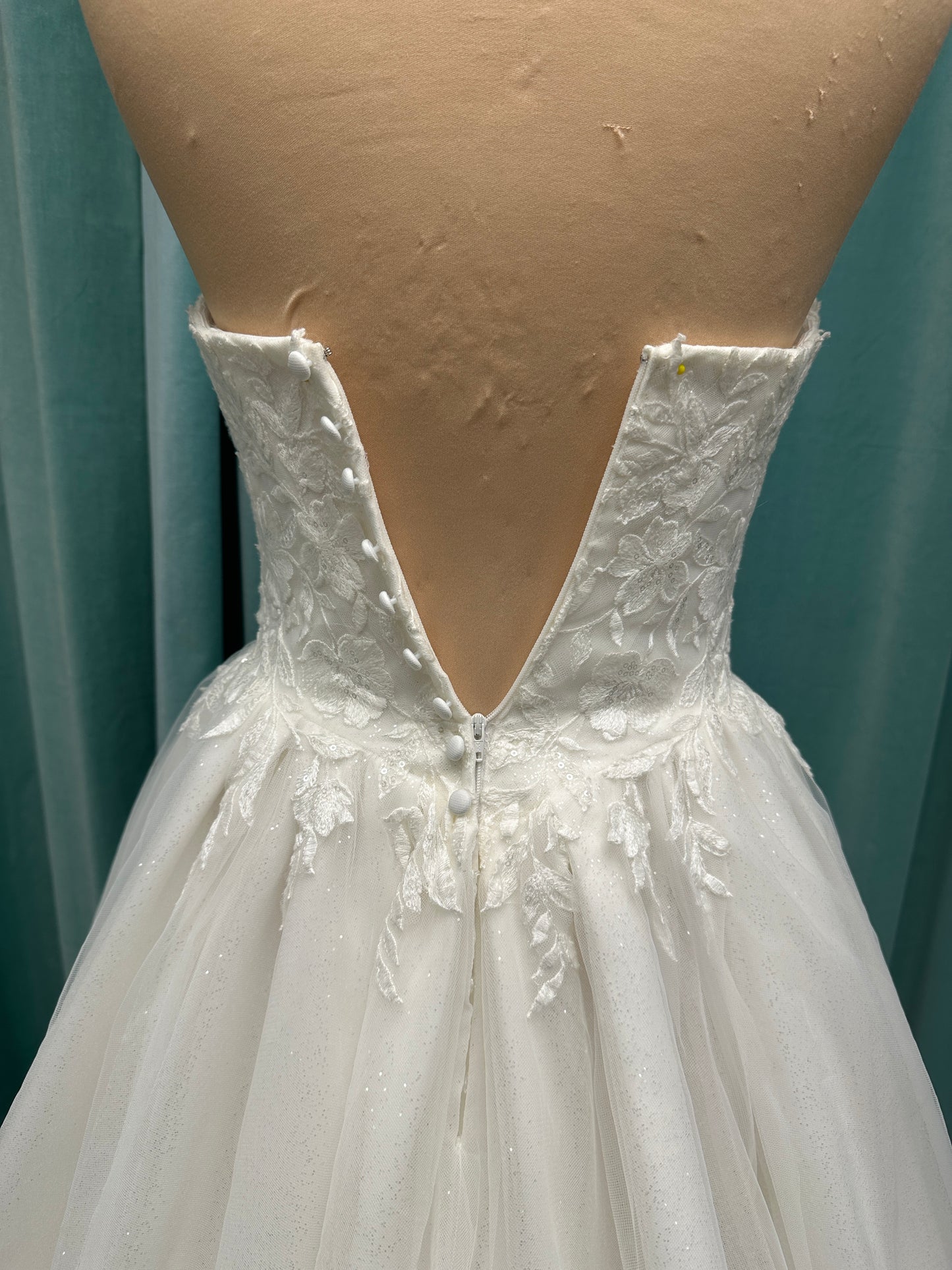 Strapless ballgown wedding dress with sheer boned bodice, sweetheart neckline, and lace appliqués flowing into a full tulle skirt