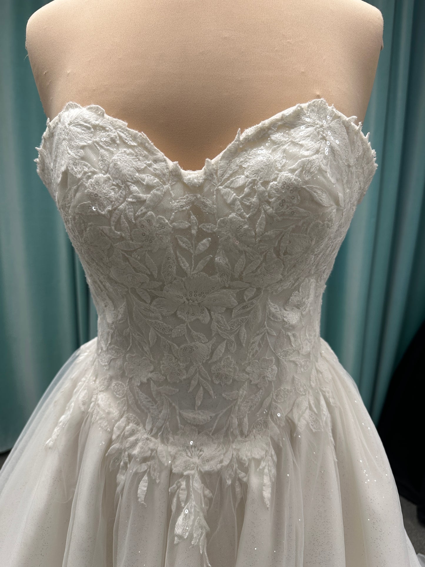 Strapless ballgown wedding dress with sheer boned bodice, sweetheart neckline, and lace appliqués flowing into a full tulle skirt