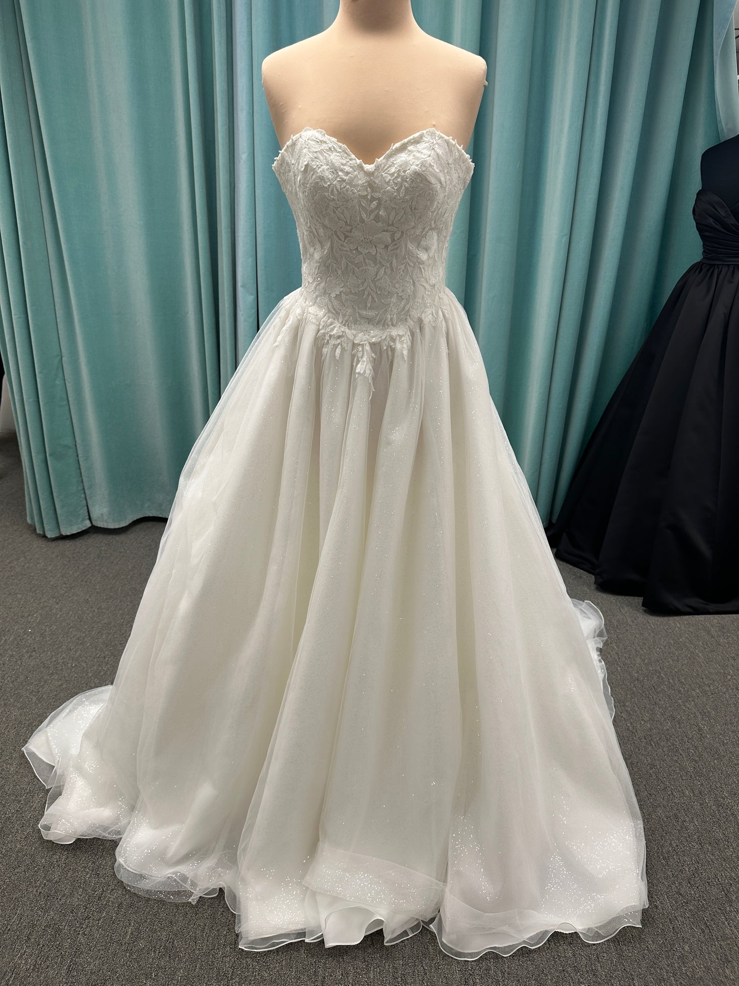 Strapless ballgown wedding dress with sheer boned bodice, sweetheart neckline, and lace appliqués flowing into a full tulle skirt