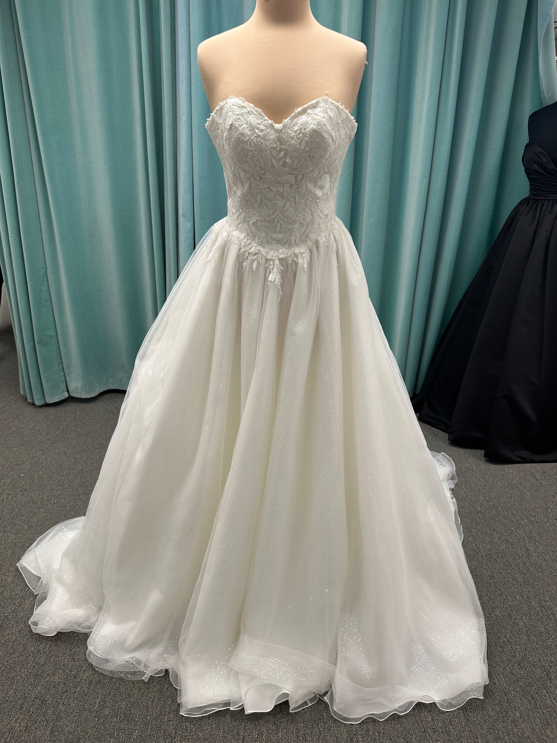 Strapless ballgown wedding dress with sheer boned bodice, sweetheart neckline, and lace appliqués flowing into a full tulle skirt
