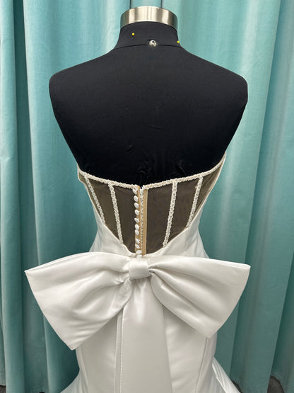 Strapless Mikado fit-and-flare wedding dress with sweetheart neckline, bow waist detail, and dramatic flared train by Stella York