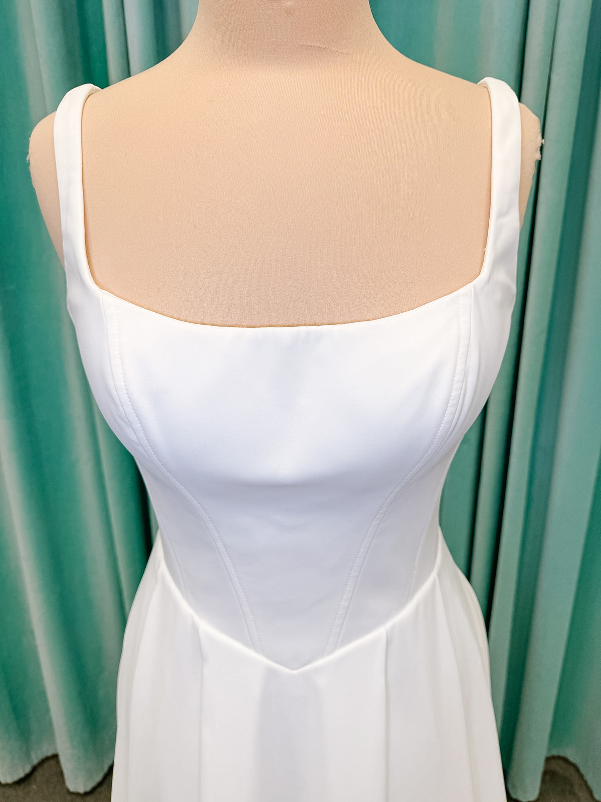 Stella York SY8180 A-line wedding dress on mannequin with wide straps, square neckline, contoured matte satin bodice, angled waist, and soft A-line skirt