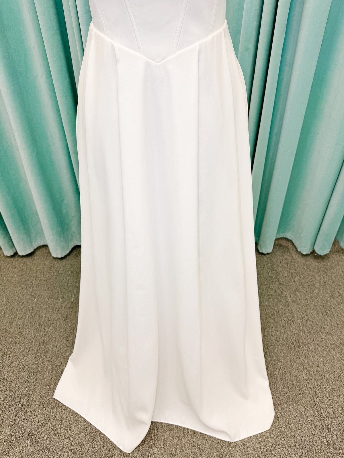 Stella York SY8180 A-line wedding dress on mannequin with wide straps, square neckline, contoured matte satin bodice, angled waist, and soft A-line skirt