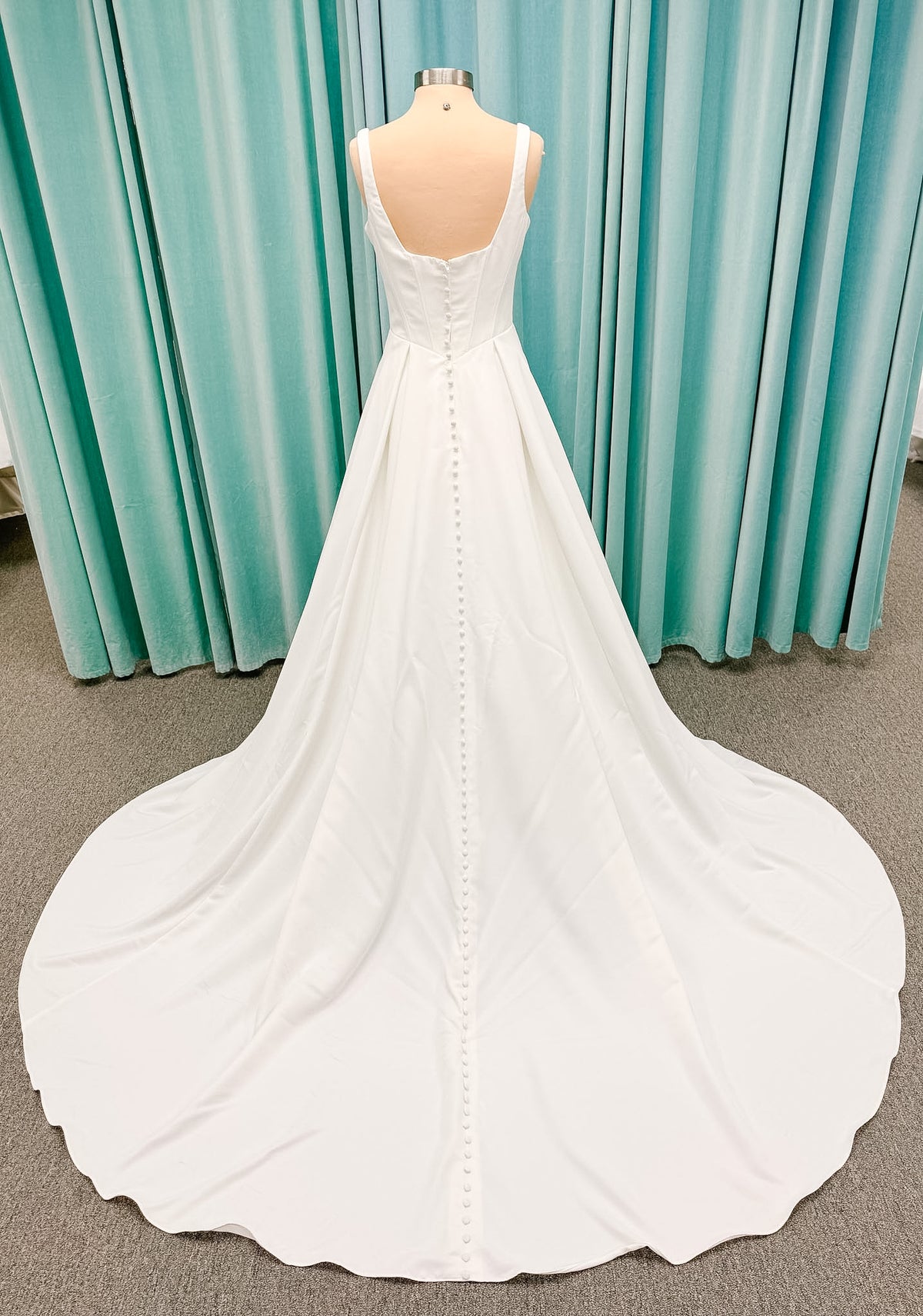 Stella York SY8180 A-line wedding dress on mannequin with wide straps, square neckline, contoured matte satin bodice, angled waist, and soft A-line skirt