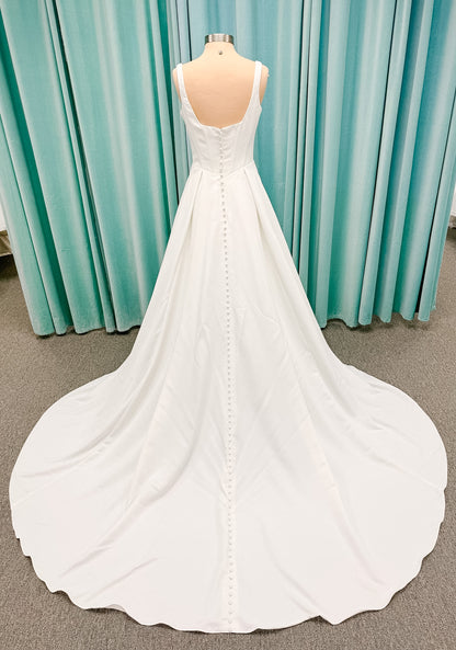 Stella York SY8180 A-line wedding dress on mannequin with wide straps, square neckline, contoured matte satin bodice, angled waist, and soft A-line skirt