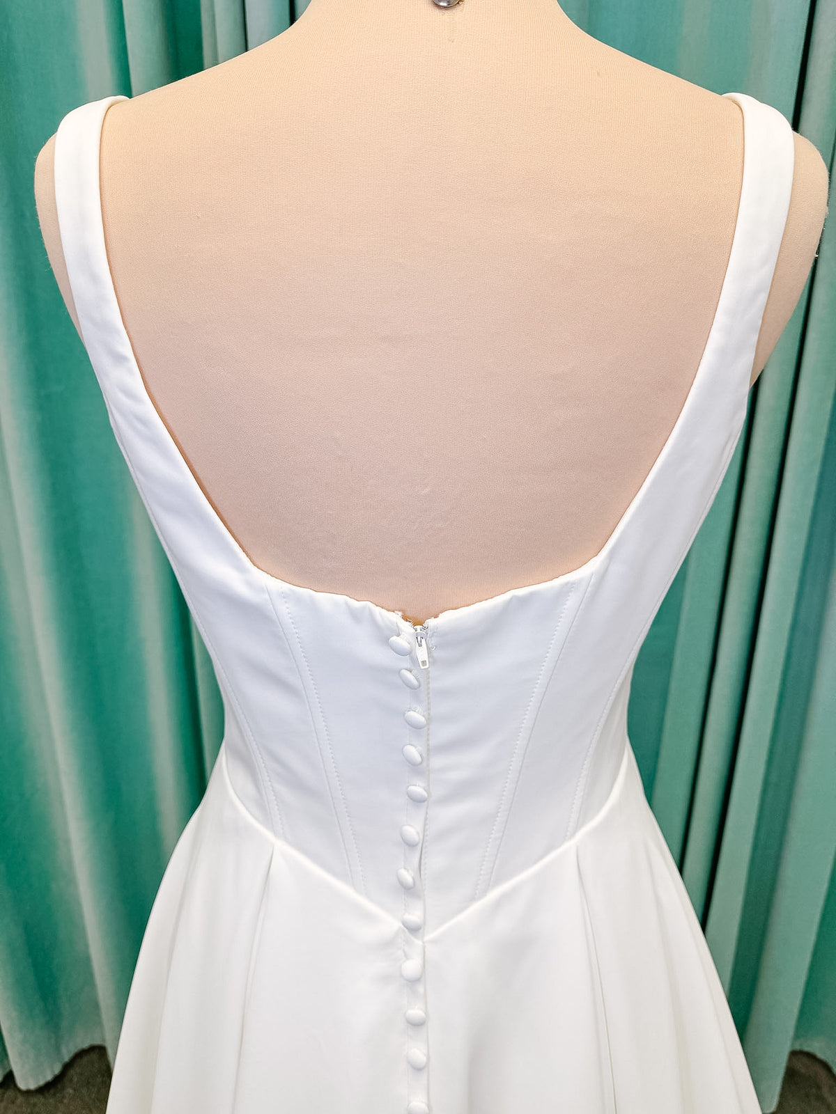 Stella York SY8180 A-line wedding dress on mannequin with wide straps, square neckline, contoured matte satin bodice, angled waist, and soft A-line skirt