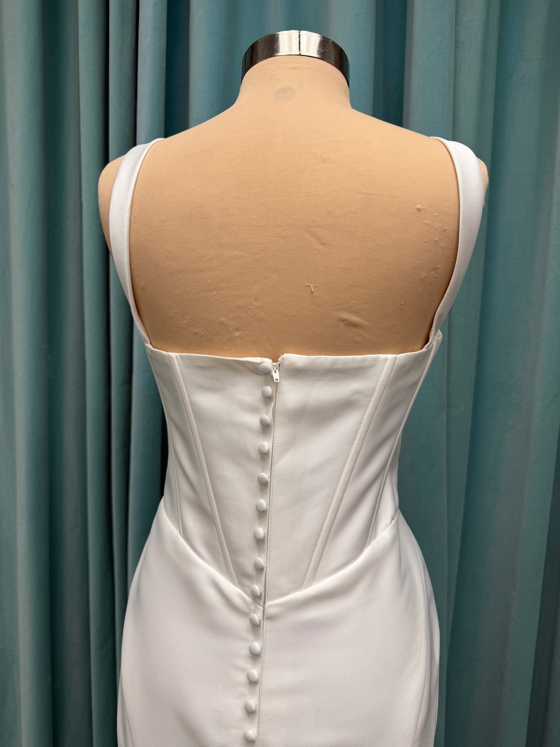 Stella York SY8148 ivory fit-and-flare wedding dress on mannequin featuring a modest scoop neckline, wide straps, and structured corset bodice.
